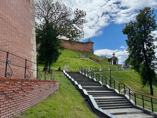 Fototapeta premium Staircase leading up to a historic site ascending the staircase, in a grassy hillside with a historic brick wall, with staircase, brick wall, tower, trees, with brick, concrete, metal texture.