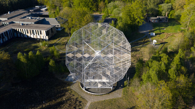 Aerial view of the Westerbork Synthesis Radio Telescope, a large octagonal metal structure surrounded by lush green trees and research buildings in Zwiggelte, Drenthe, Netherlands.