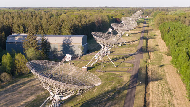 Aerial view of the Westerbork Synthesis Radio Telescope with its array of large parabolic dishes aligned along a path through the forest in Zwiggelte, Drenthe, Netherlands.