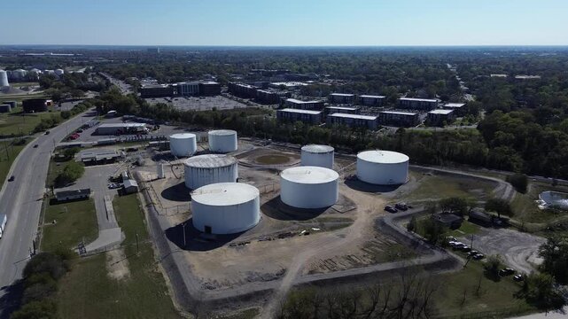 Clusters of white cylinders sit amidst cleared dirt patches near Cooper River high volume freight industrial zones. High angle vistas capture uniform drum roofs glowing under North Charleston, SC
