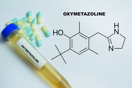 Concept of oxymetazoline nasal decongestant write on book isolated on Wooden Table. For relief of nasal congestion and sinus pressure