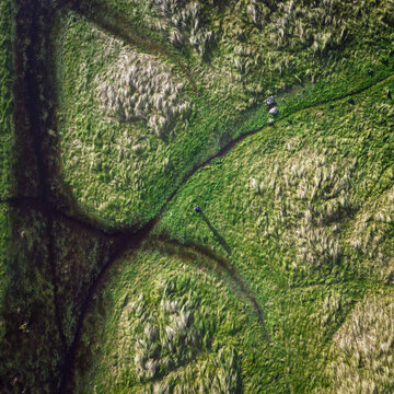 Aerial view of the grassy landscape and walking trails of Howth with a person walking along the path in Dublin, County Dublin, Ireland.