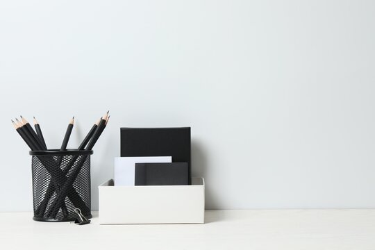 Front view of a minimalist home workspace with office supplies and copy space. White desk against a white wall.