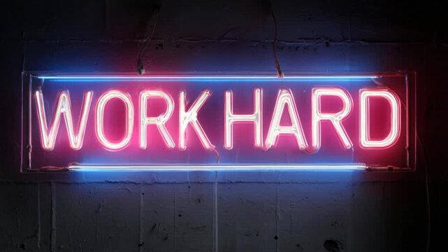 Flickering neon sign with the motivational phrase work hard hanging on a dark concrete wall