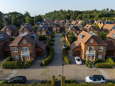 Aerial view of luxury new build homes with manicured hedges, paved driveways, and parked cars in a quiet residential neighborhood in Maidenhead, England, United Kingdom.