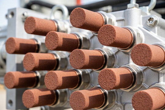 Close-up of industrial hydraulic pump manifold with multiple bronze silencers