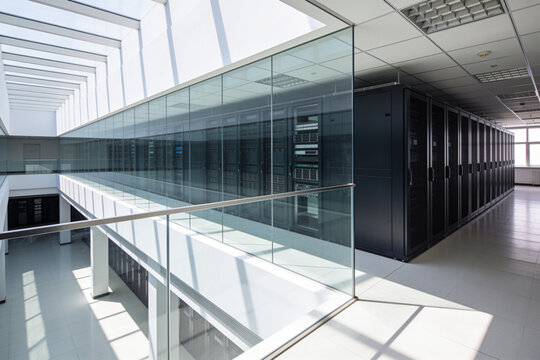 Modern data center with rows of server racks behind glass walls