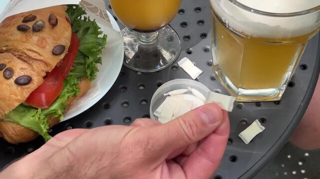 two men hands taking nicotine pouches from container on table with croissant sandwich outdoors with copyspace concept of tobacco alternative and lifestyle habit for adults with mockup and template