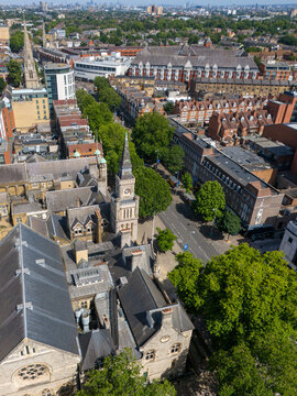 Aerial view of Ealing Town Hall with its prominent clock tower surrounded by historic brick buildings, lush green trees, and urban streets in London, England, United Kingdom.