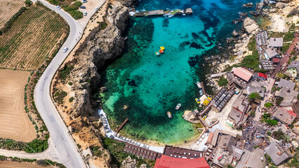 aerial drone view of anchor bay on south malta coast with crystal clear Mediterranean Sea water and boats with cliffs surrounding in summer © STJMEDIA