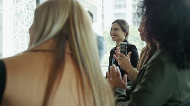 Engaged professionals share laughter and applaud during a presentation or discussion at a business event. The group shows enthusiasm, collaboration, and positive interaction in a corporate setting.