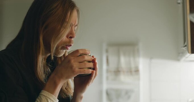 Caucasian man drink hot water in evening. Single male is drinking tea at kitchen at home. 4K 10-bit
