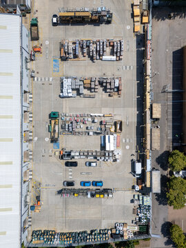 Aerial view of a builders merchants yard with organized rows of construction materials, pallets, and parked vehicles in London, England, United Kingdom.