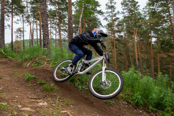 Fototapeta premium Athlete racer riding at speed on forest trail during downhill competition