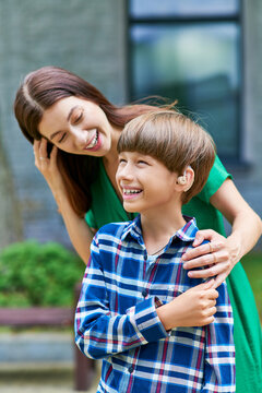 A mother shares a joyful moment with her hearing impaired son outdoors.