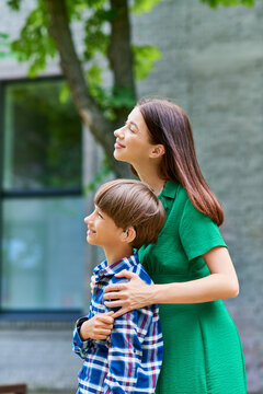 A mother joyfully embraces her hearing impaired son in a park.