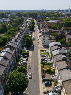 Aerial view of Ealing residential streets with rows of Victorian terraced houses, parked cars, and lush green trees in the London Borough of Ealing, England, United Kingdom.