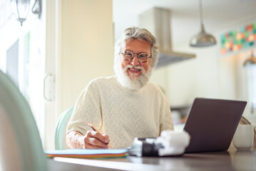 Fototapeta premium Elderly gentleman thoughtfully reviews his finances at the kitchen table