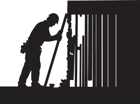 Silhouette of a man working on a damaged gate or fence worker