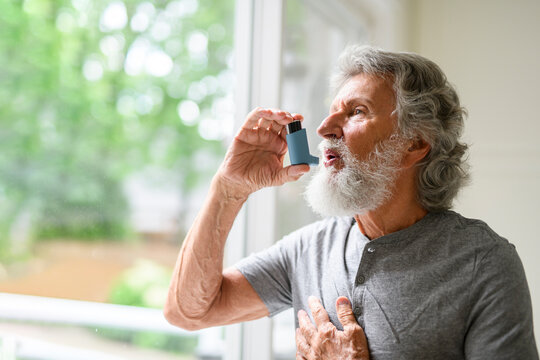 senior men using asthma inhaler at home house
