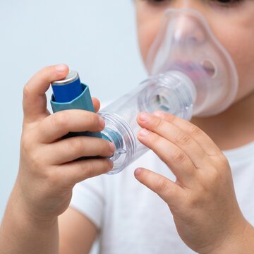 Child Hands Using Metered Dose Inhaler with Spacer for Proper Pediatric Asthma Treatment