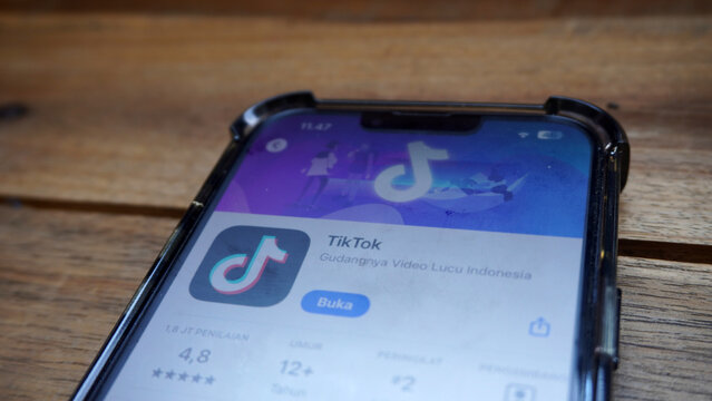 Purwokerto, Indonesia - 17 June 2026: Close-up of an iPhone screen showing the TikTok app listing on the App Store, resting on a wooden table.