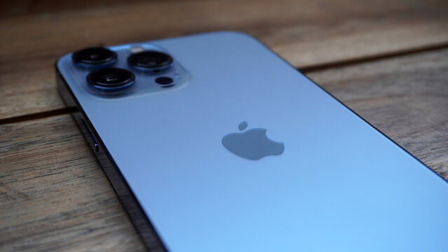 Purwokerto, Indonesia - 17 June 2026: Close-up of iPhone's triple camera lenses and Apple logo resting on a wooden table.