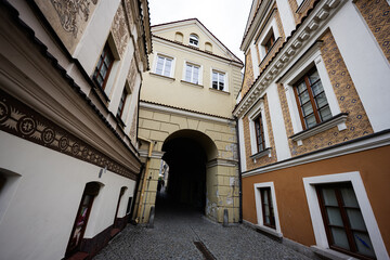 Historic narrow archway and cobblestone street in Lublin Poland with decorated facades, ornate windows and atmospheric alleyway in the old town city center © AS Photo Family
