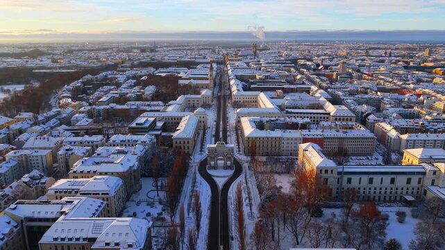Cinematic aerial footage of Munich landmark Siegestor near LMU University. Fresh snow, winter morning light and historic architecture in the city center.