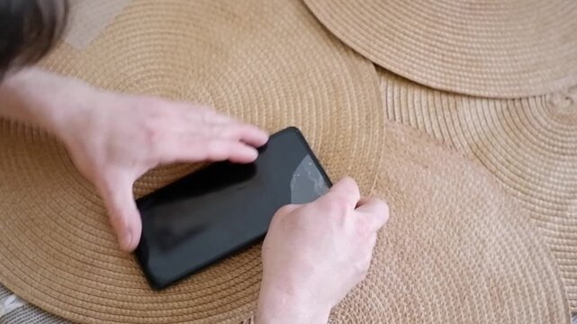 Male hands carefully applying a new protective glass film on a smartphone screen at home
