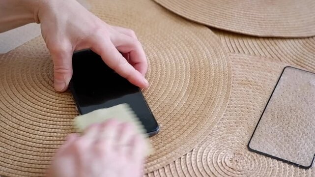Male hands cleaning a mobile phone screen with a cloth before applying a protective tempered glass