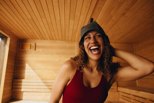Woman laughing in sauna for wellness relaxation and spa self care portrait