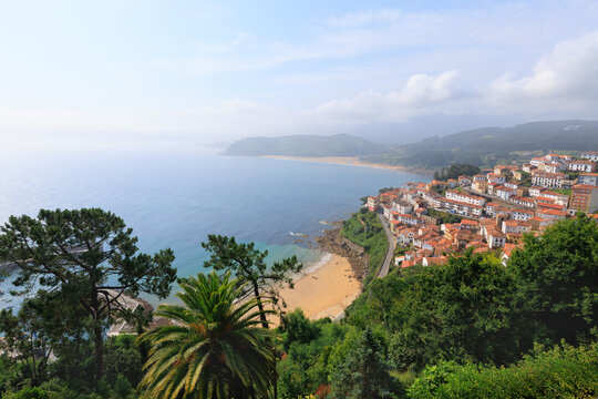 Aerial view of the charming town of Lastres with its white houses, bay, and mountains on a hazy day in Asturias, Spain