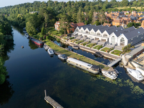 Aerial view of luxury homes and residential real estate along the river Thames with moored narrowboats and cruisers in Maidenhead, England, United Kingdom.