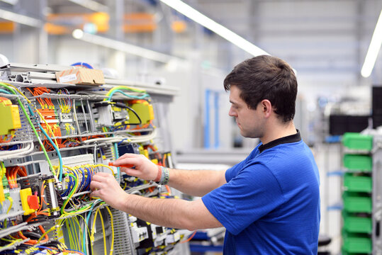 young apprentice assembles components and cables in a factory in a switch cabinet - workplace industry with future