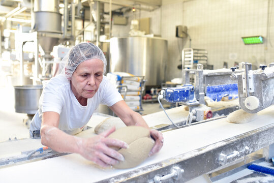 Worker in a large bakery - industrial production of bakery products on an assembly line