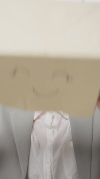 Vertical Screen : Young Asian businesswoman wear draw smile mask paper bag hide feel bad mood with fail work at office. Anonymous young lady mad annoying and blame with overwork, Work mental health.