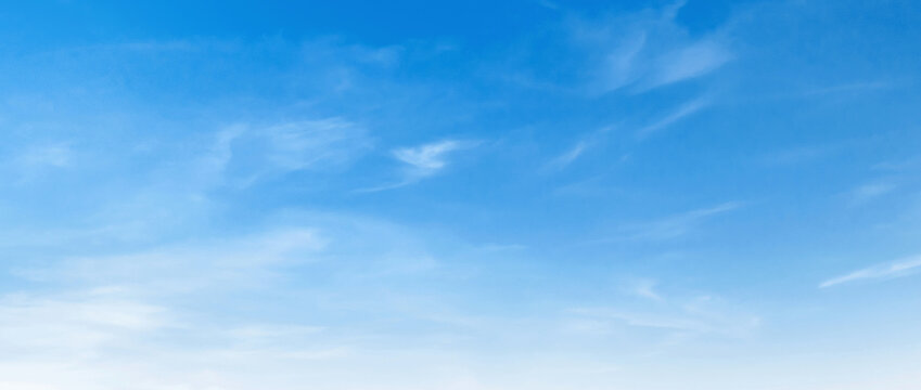 Clear blue sky with wispy, soft clouds drifting gently