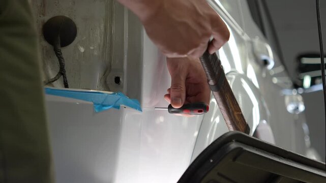 Paintless Car Dent Repair. Process of paintless dent repair on car body. PDR. The mechanic at the auto shop with tools to repair dents in car body. Body repair. A specialist repairs a dent on the car.