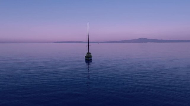 Anchored Sailboat on Calm Open Sea Near Verga and Kalamata, Greece, Aerial Dawn View of Peaceful Yacht, Pastel Sky, Distant Coastline and Mediterranean Bay
