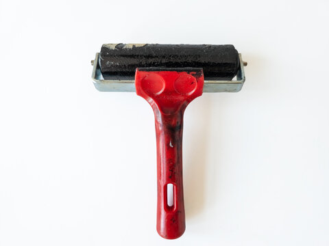 An ink roller for printmaking with a red handle isolated on a white background