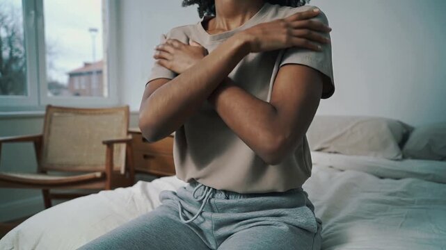 Closing eyes woman crossing arms, lifting chin, opening eyes on bed, wearing tan tee for grounding