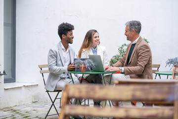 three business people having a meeting for a briefing outside the office with laptop and tablet © Guirado