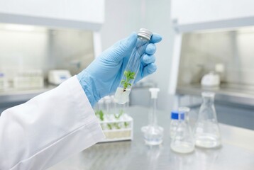 Fototapeta premium Scientist in blue lab gloves holding a test tube with a green plant seedling in a modern laboratory