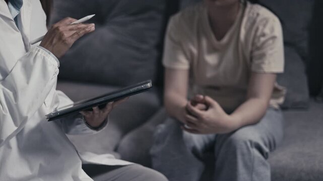 Professional caregiver writing clinical notes during a mental health consultation with a depressed teenager. Therapy, healthcare, support, wellbeing, recovery, empathy, 4K.