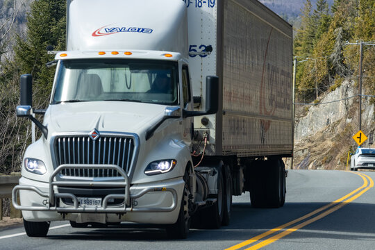 Quebec, Canada, 24 April 2026 : A white Valois International semi truck with a trailer drives on a winding mountain road.