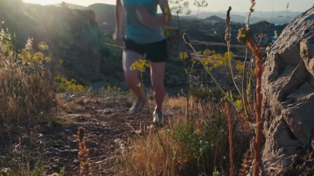 Woman running with determined stride on a rugged mountain trail at golden hour, embodying freedom and personal challenge through outdoor adventure.