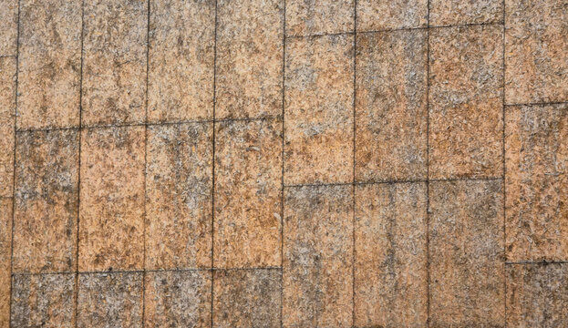 Rough textured surface of weathered oriented strand board wall panels creating a brown wooden background