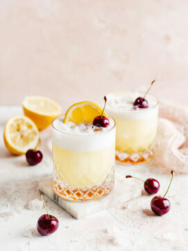 Amaretto Sour cocktail made with amaretto liqueur, lemon juice, and sweetener, balanced with bourbon and egg white for a frothy texture, and garnished with a cherry and orange slice