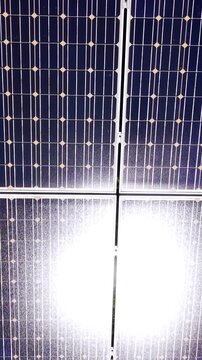Macro view of solar panel cells with sunlight glare. Deep blue photovoltaic grid meets a bright overexposed section from direct reflection. Vertical video.